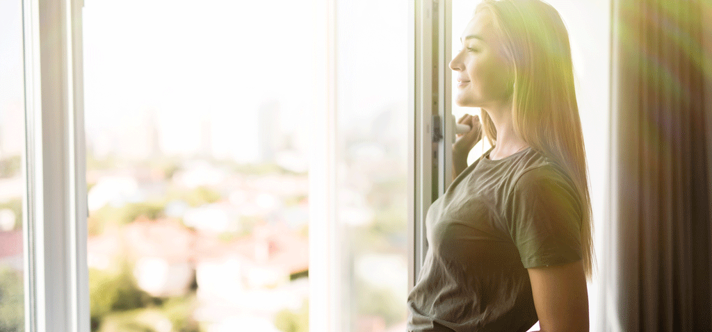 Mujer abriendo ventana para mejorar la calidad del aire